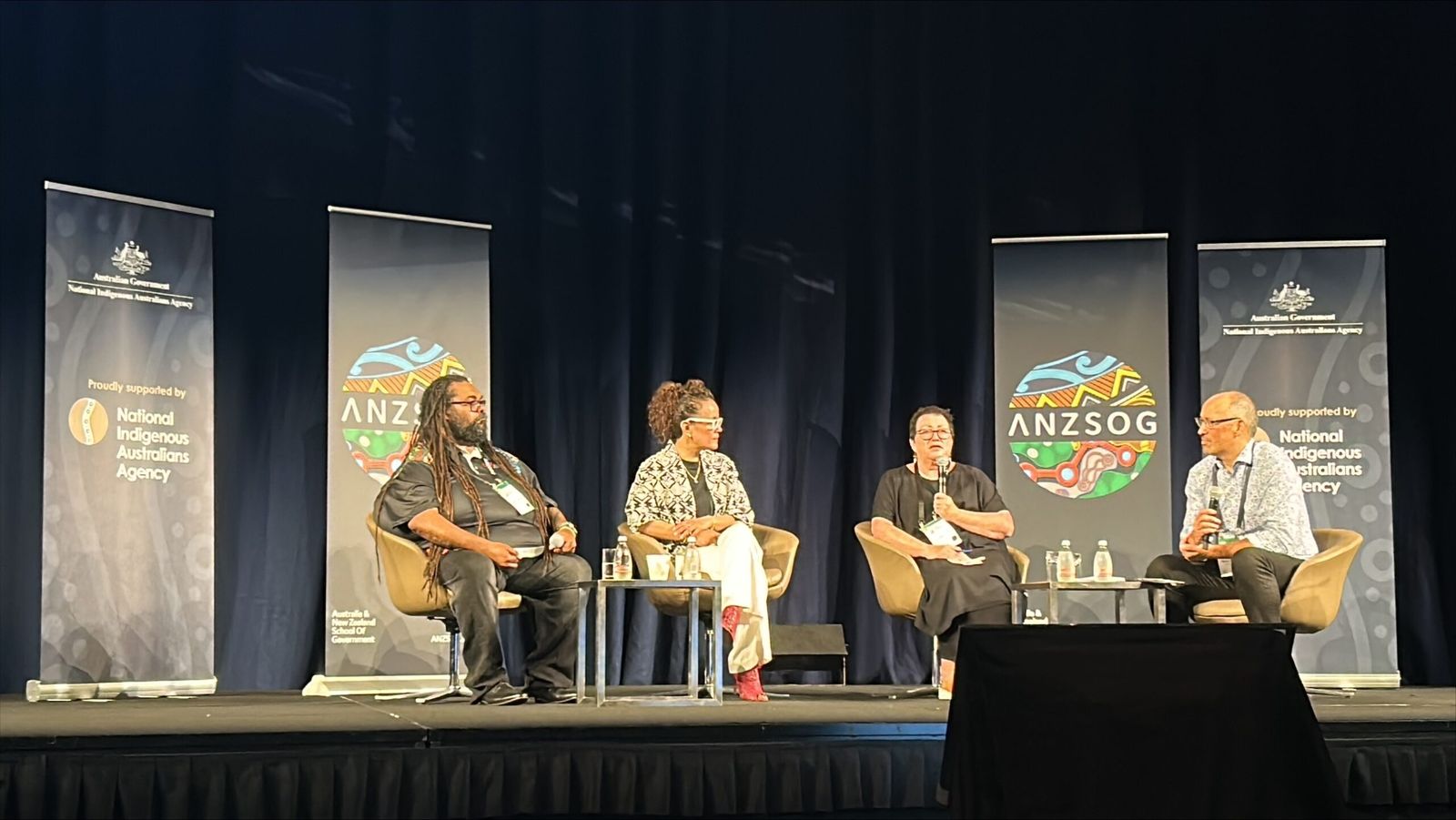 Four panellists on stage at the 2023 First Nations Public Administration Conference, in front of ANZSOG and National Indigenous Australians Agency banners