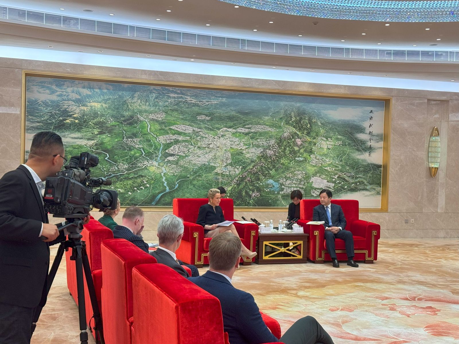 ANZSOG China Reciprocal Program participants in a formal meeting with Chinese officials in a large reception room, filmed by a camera operator