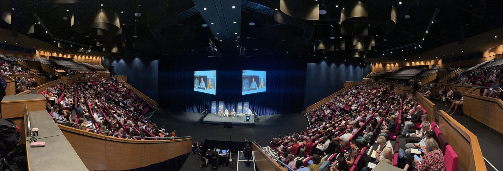 Wide view of a full auditorium at the 2023 First Nations Public Administration Conference, with a panel on stage