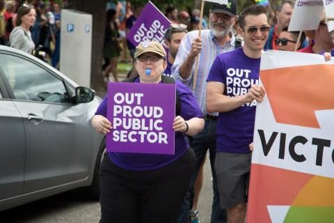 Marchers in purple 'Out Proud Public Sector' T-shirts carrying placards at a Pride march