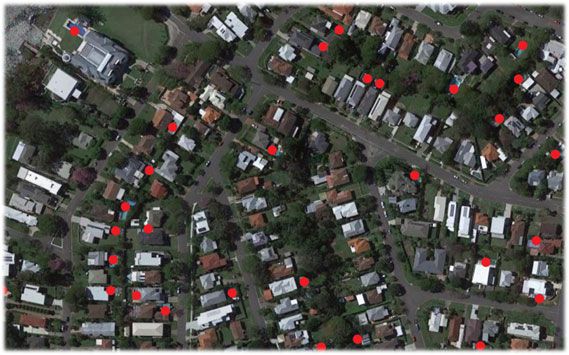 Aerial photo of a suburb with red dots marking properties flagged by AI-assisted analysis