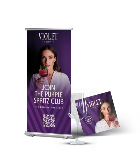 Violet Werbebanner mit einer Frau, die einen Cocktail in der Hand hält, und dem Text „Join the Purple Spritz Club”, gepaart mit einem lila Getränkebooklet und einem Violet Glas mit Markenlogo Violet.
