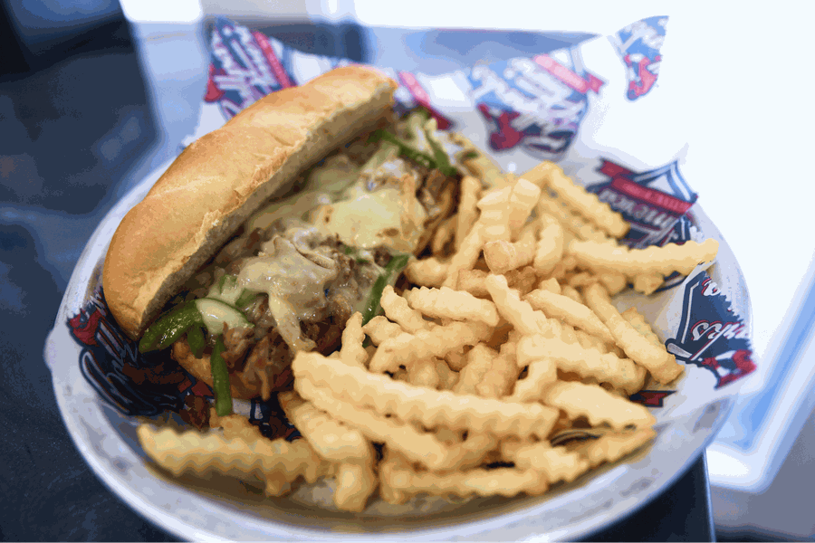 A pulled pork sandwich with melted cheese and green peppers served with waffle fries.