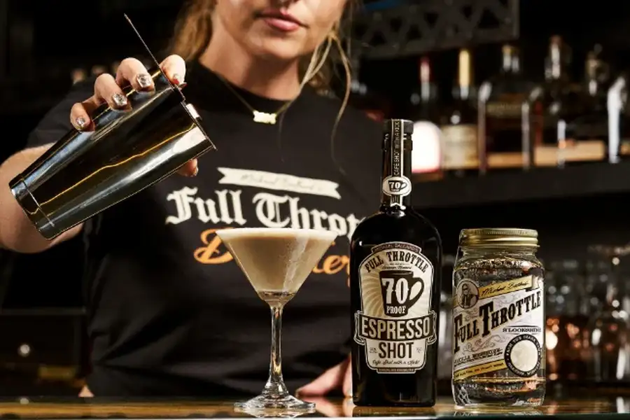 Bartender pouring cocktail with Full Throttle espresso shot and whiskey bottles displayed.