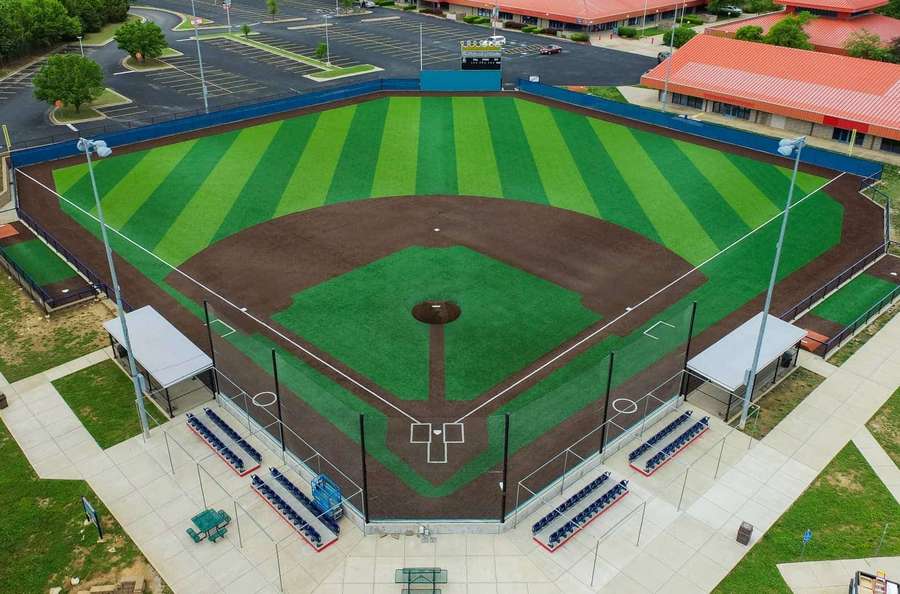 Aerial view of a well-maintained baseball field with striped grass and dugouts.