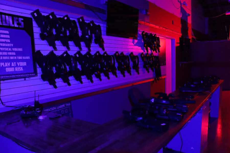 Indoor laser tag arena with illuminated purple and red neon lighting and silhouetted player figures.