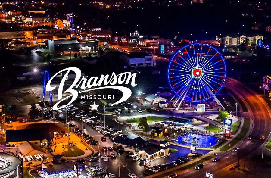 Aerial nighttime view of Branson, Missouri's entertainment district with illuminated Ferris wheel and attractions.