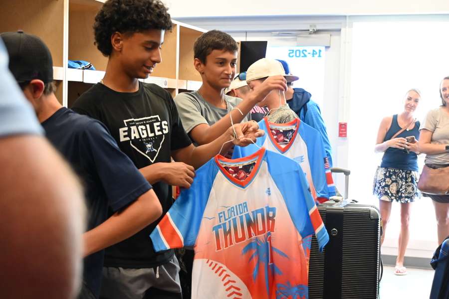 Teenagers help a younger child try on a Florida Thunder sports jersey and medal at an indoor event.
