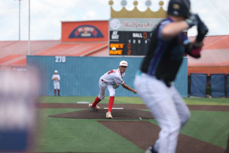 A baseball pitcher in white and red uniform prepares to throw the ball during a game.