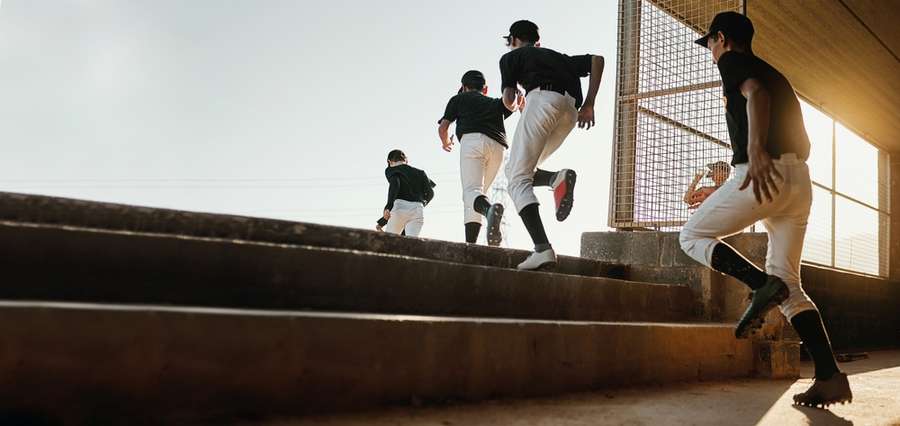 Young baseball players in uniforms running on dirt field during practice or game.