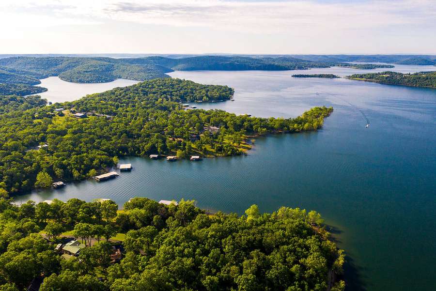 # Aerial view of a pristine lake surrounded by dense green forests with scattered waterfront homes and docked boats.