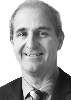 Smiling man in a suit and tie, with a close-cropped hairstyle. Black and white portrait.