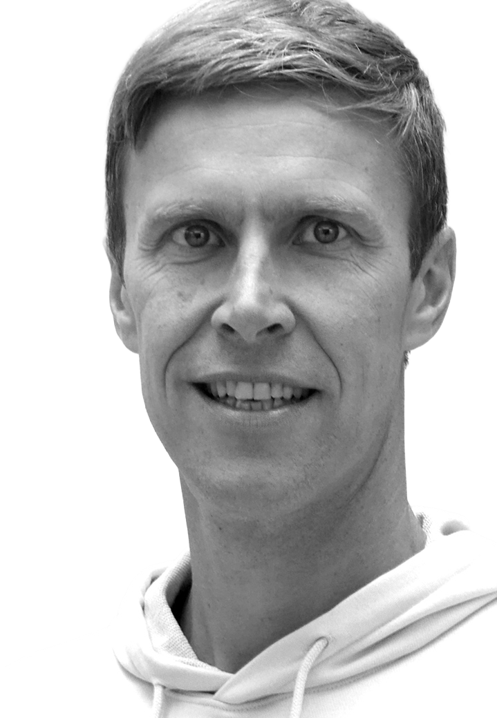 Portrait of a smiling man in a white hoodie with short hair, looking directly at the camera against a plain white background.