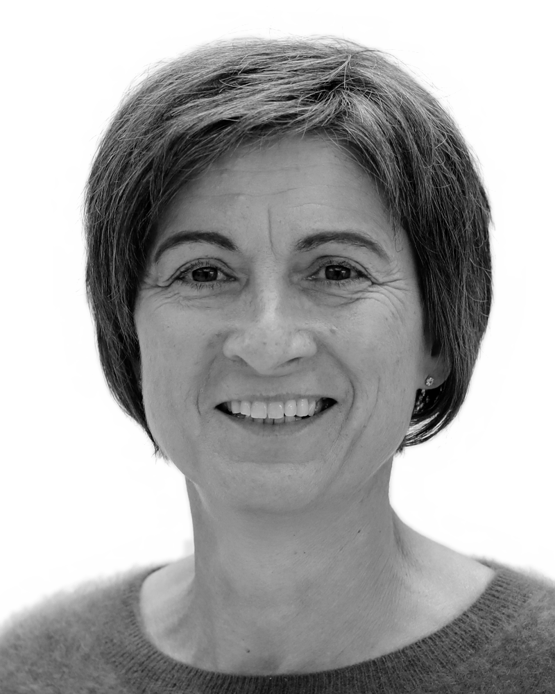 A grayscale portrait of a smiling woman with short hair and wearing a sweater, looking directly at the camera.
