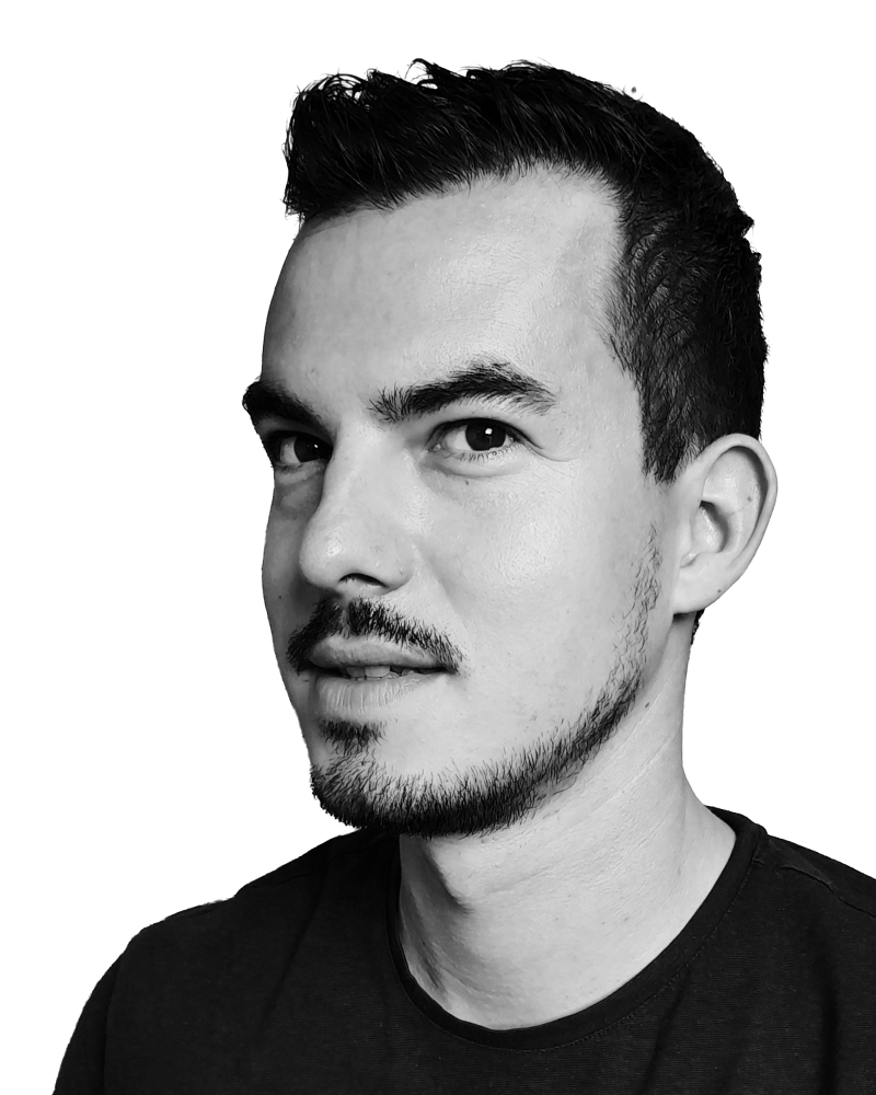 Black and white portrait of a person with short dark hair and a trimmed beard, looking slightly to the left against a plain background.