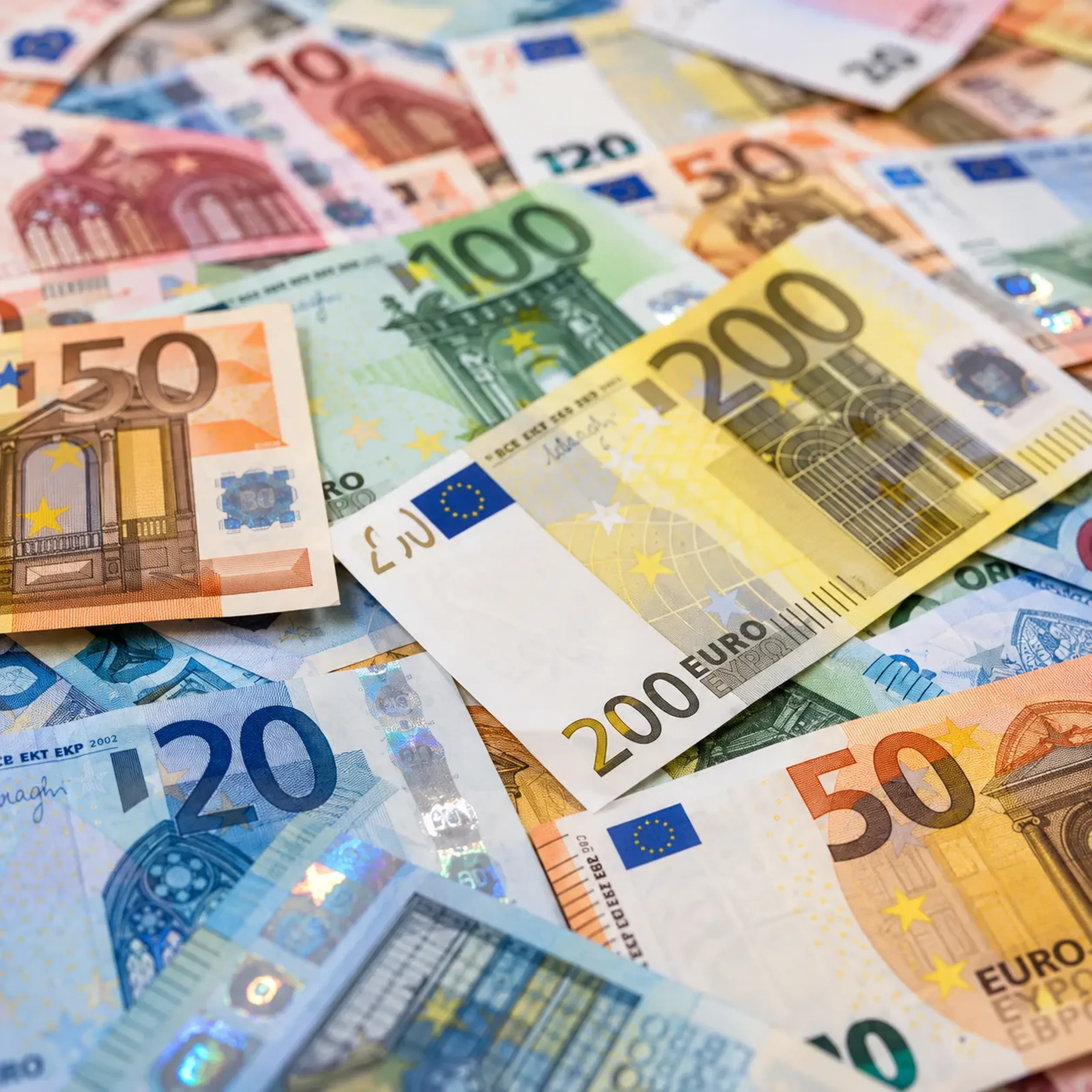 Verschiedene Euro-Banknoten in unterschiedlichen Werten liegen überlappend auf einem Tisch.