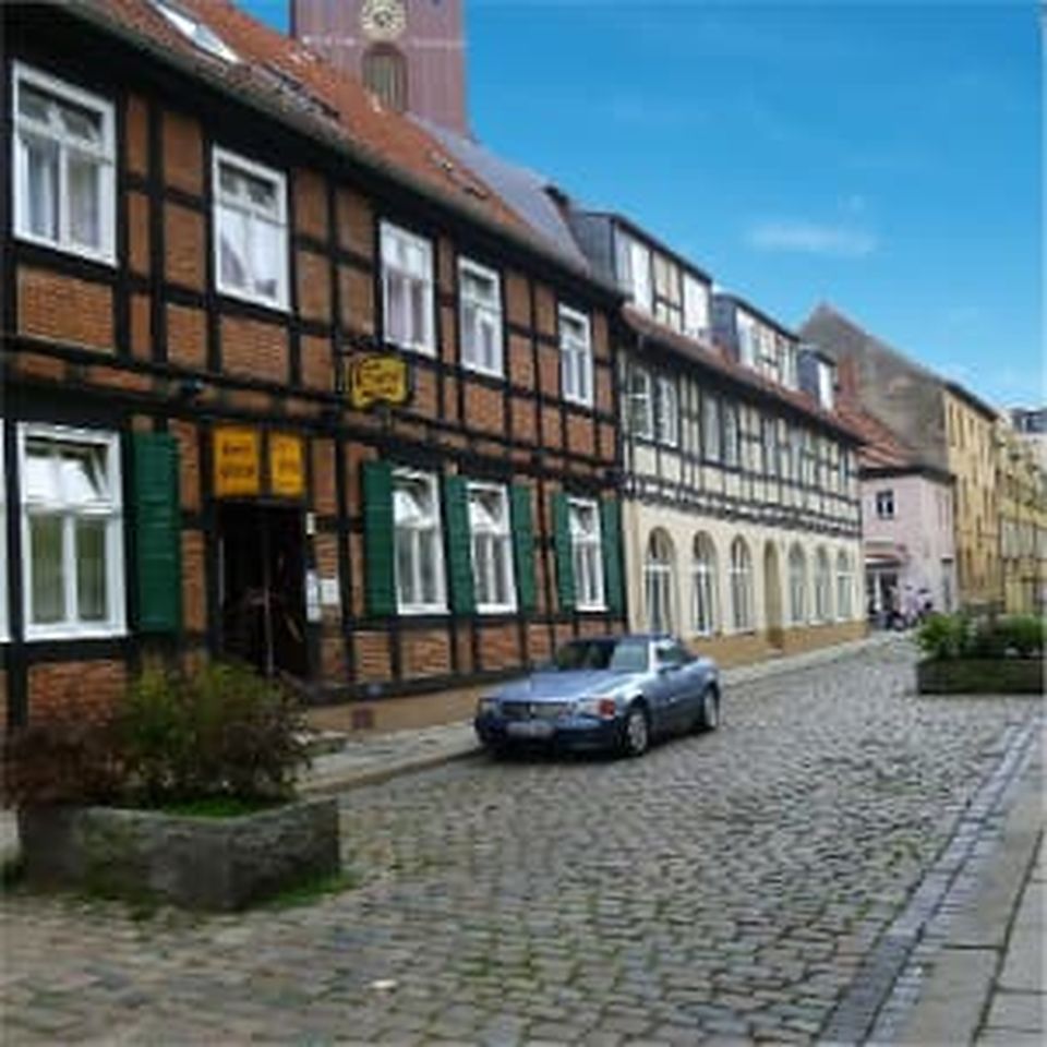 Wohngebäude in Berlin bei Sonnenuntergang, mit Blick auf den Fernsehturm und herbstlichen Bäumen im Vordergrund.