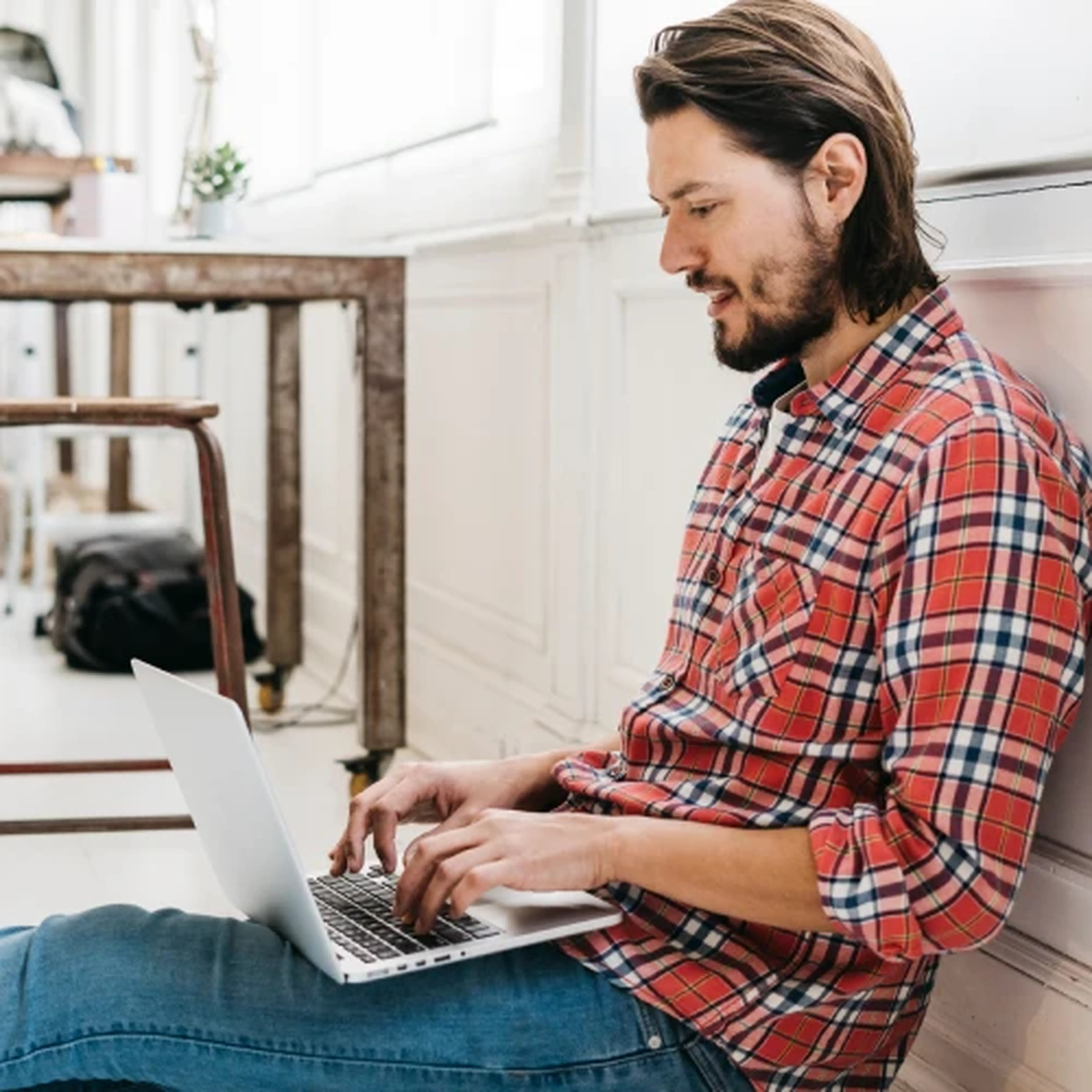 Symbolbild - Junge männliche Person bei Antragstellung der Prozesskostenhilfe mit einem Laptop sitzend auf weißem Boden