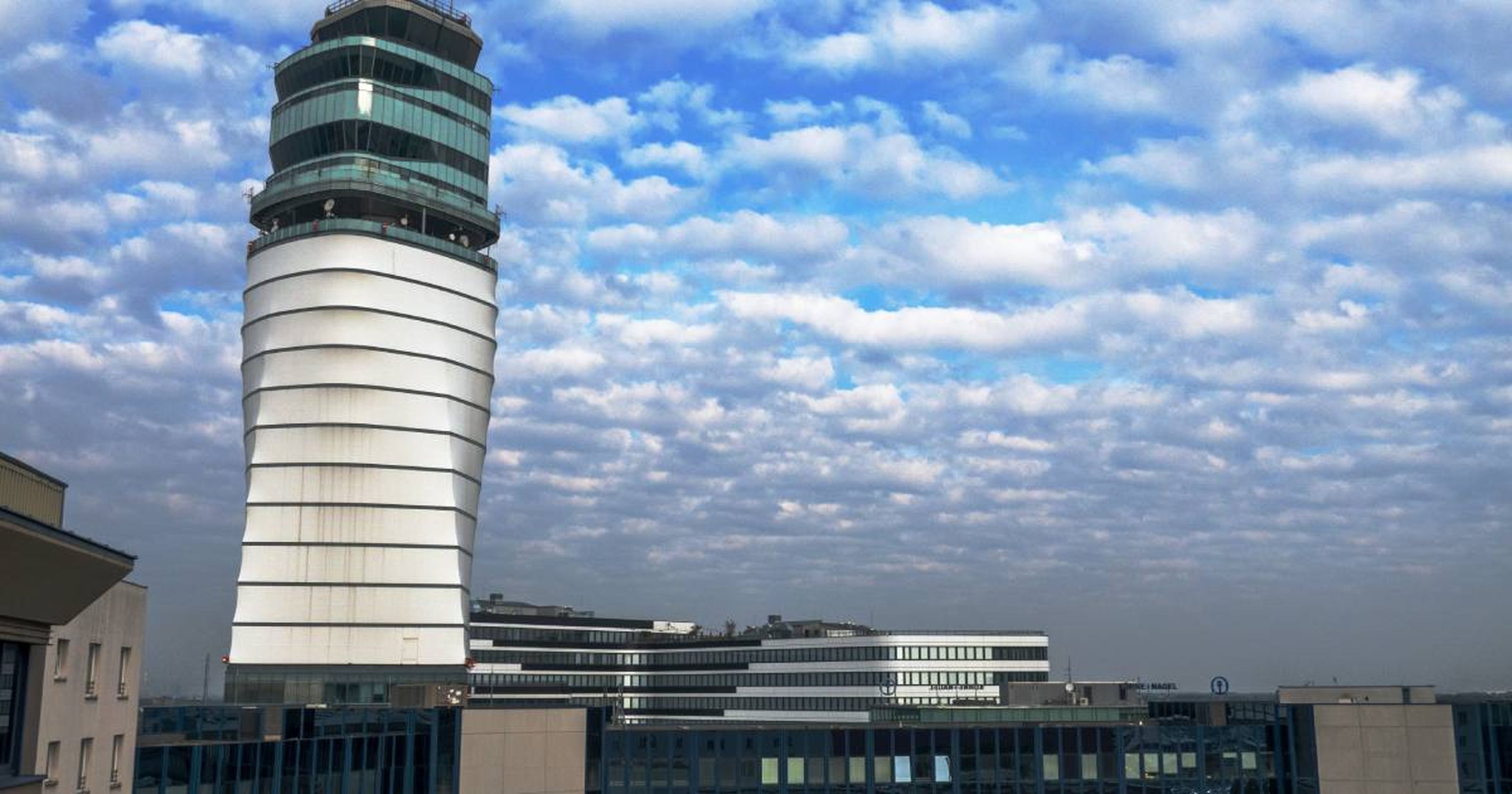 Moderne Flughafen-Besprechungsturm unter blauem Himmel mit Wolken am Wiener Flughafen.