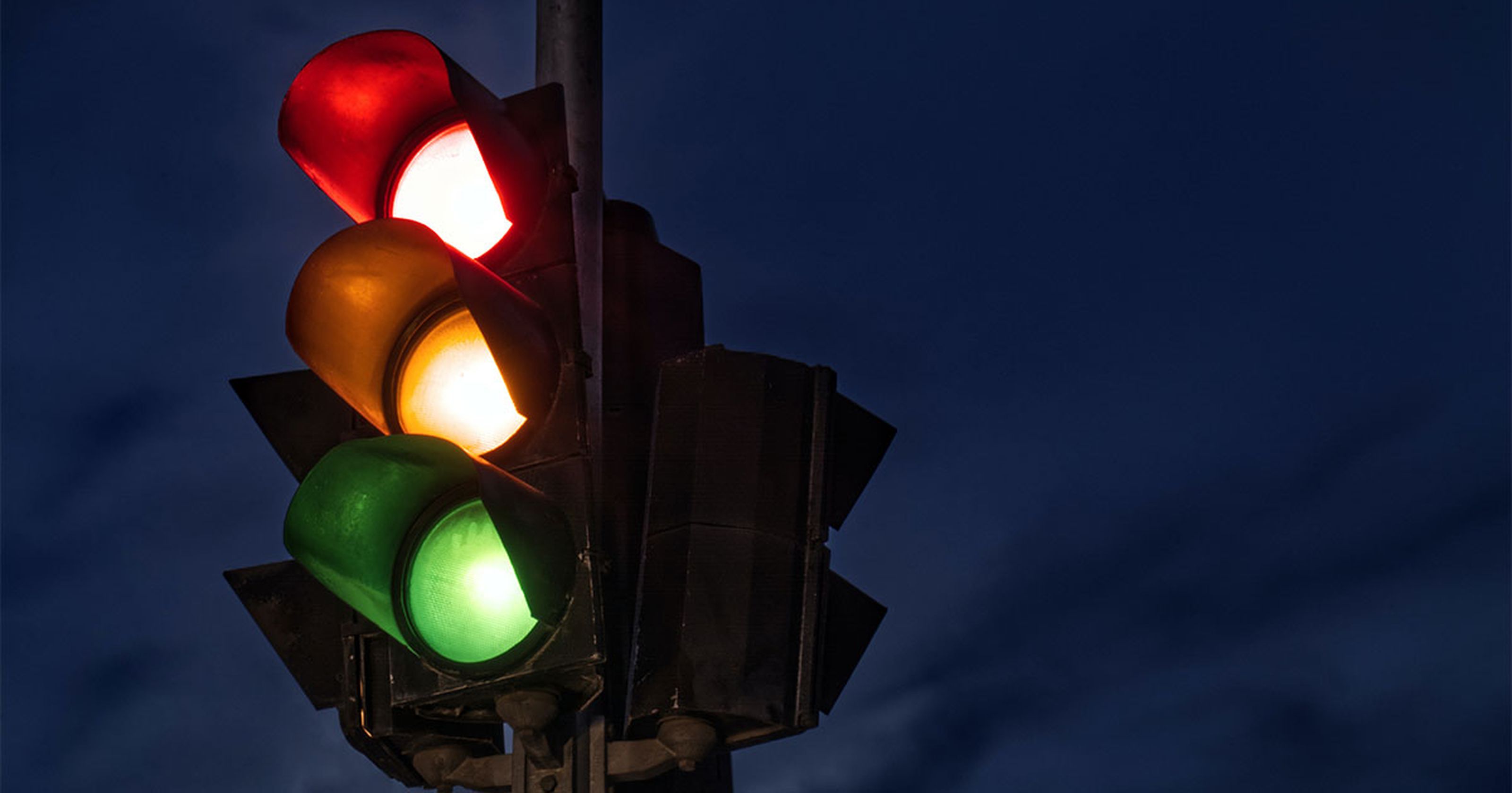 Darstellung einer Verkehrsampel. Ampel leuchtet in allen 3 Farben bei Nacht.