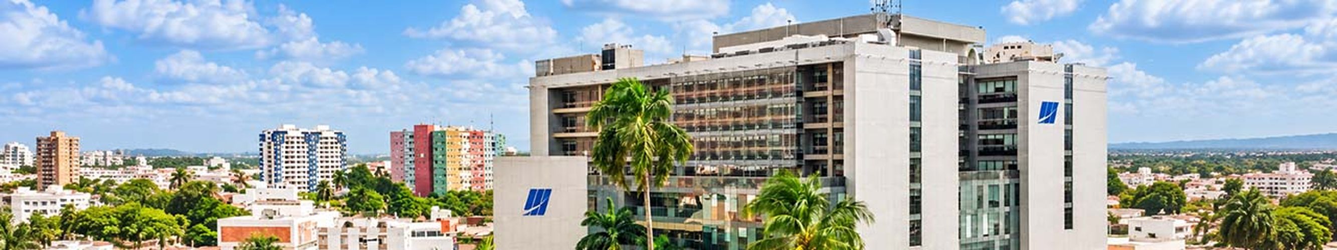 View of a multi-story office building with balconies and a blue logo under a partly cloudy sky.