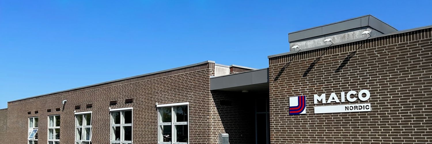 Backsteinbau mit mehreren Fenstern und dem Schriftzug 'MAICO NORDIC' an der Fassade.