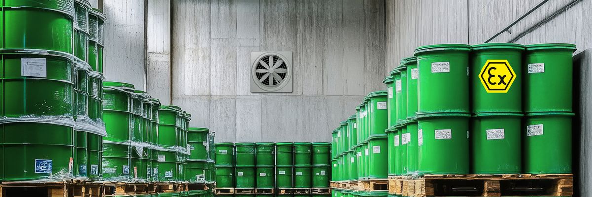 Grüne Fässer mit Warnsymbol 'Ex' auf Holzpaletten in einem Lagerraum mit Betonwänden und Ex-Ventilator an der Wand.