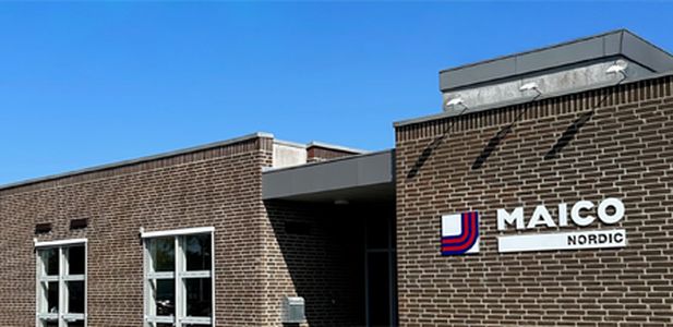 Backsteinbau mit mehreren Fenstern und dem Schriftzug 'MAICO NORDIC' an der Fassade.