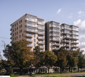 Multi-story residential building with balconies and glass railings against a blue sky
