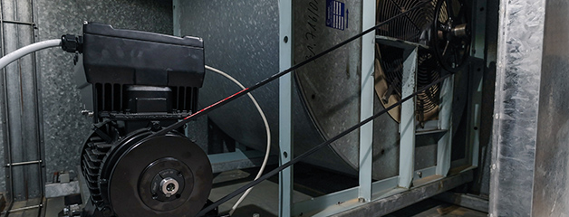 Black-and-white close-up of an electric motor with belt drive inside a technical housing