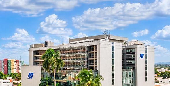 View of a multi-story office building with balconies and a blue logo under a partly cloudy sky.