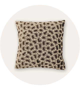 Vierkant sierkussen met een beige en bruin organisch kiezelachtig patroon tegen een lichte achtergrond.