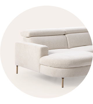 Moderne off-white hoekbank met afgeronde chaise longue, lage rugleuning en slanke metalen poten tegen een lichte neutrale achtergrond.