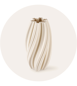 Crèmekleurige keramische vaas met een gedraaid, geplooid ontwerp en een onregelmatige golvende rand tegen een egale lichte achtergrond.