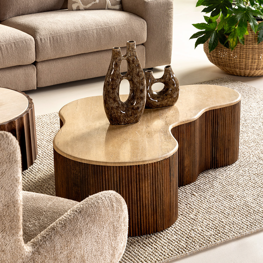 Salontafel van hout met een organische vorm en een glad blad, sculpturale vazen en neutraal getextureerde zitmeubels in een gezellige woonkamer.