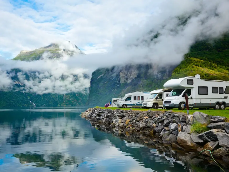 Wohnmobile aufgereiht neben einem See