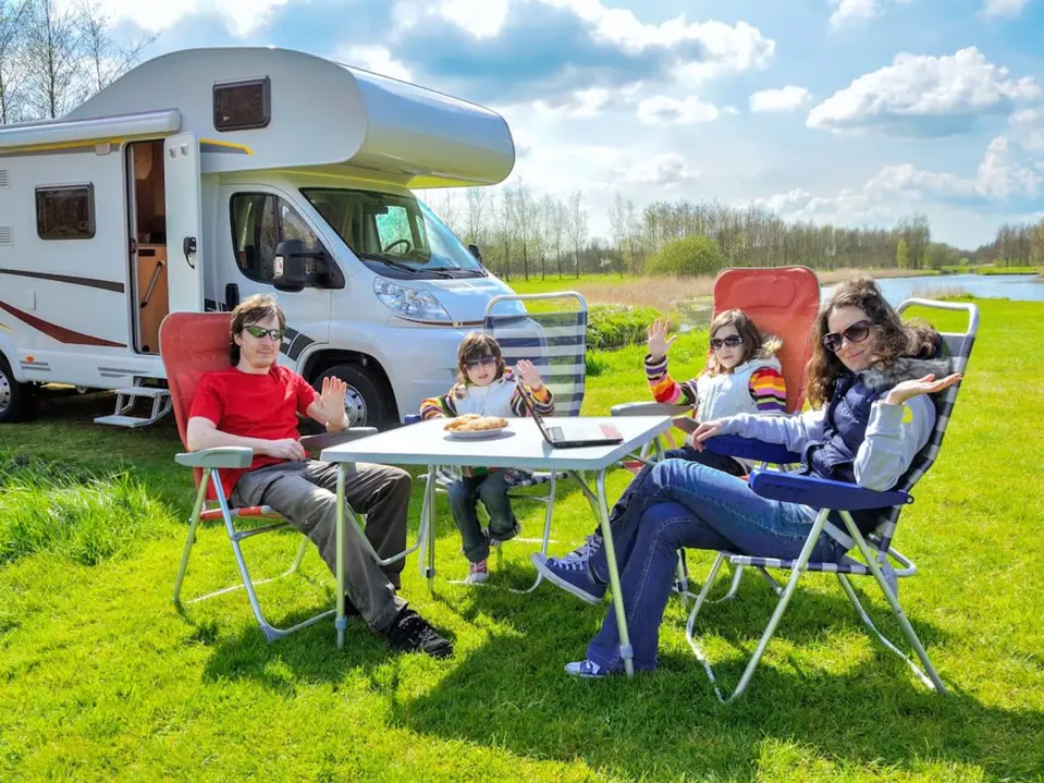 Familie beim Picknick vorm Wohnwagen