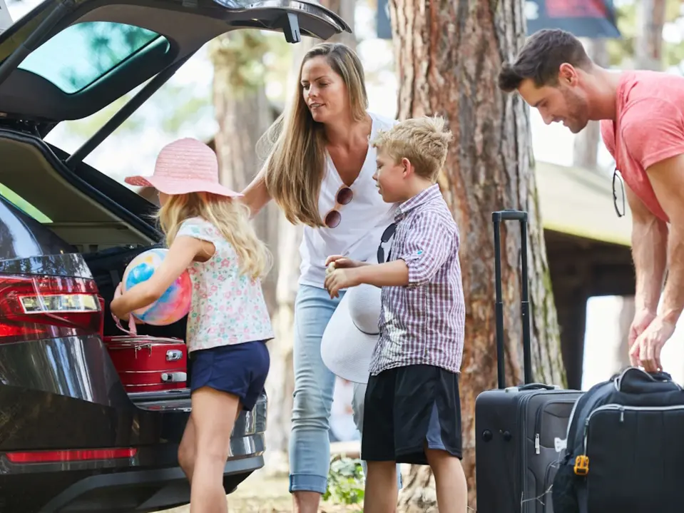 Foto einer Familie beim Einladen von Koffern in das Auto