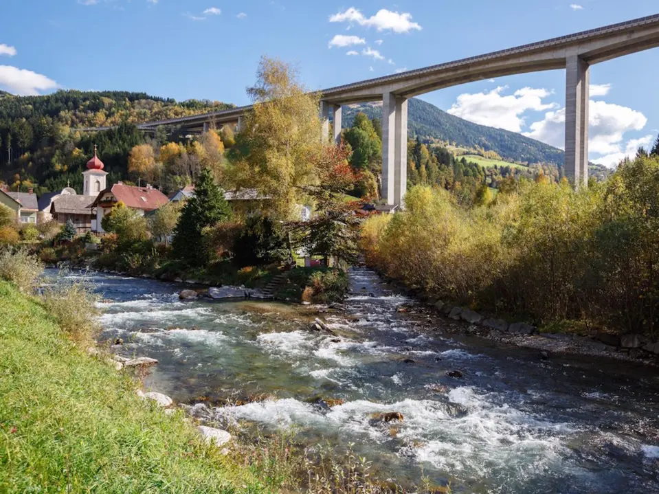 Bild einer Autobahn über einem Fluss und ein Dorf gebaut