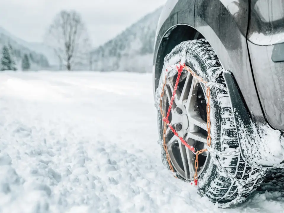 Auto mit montierten Schneeketten in Winterlandschaft