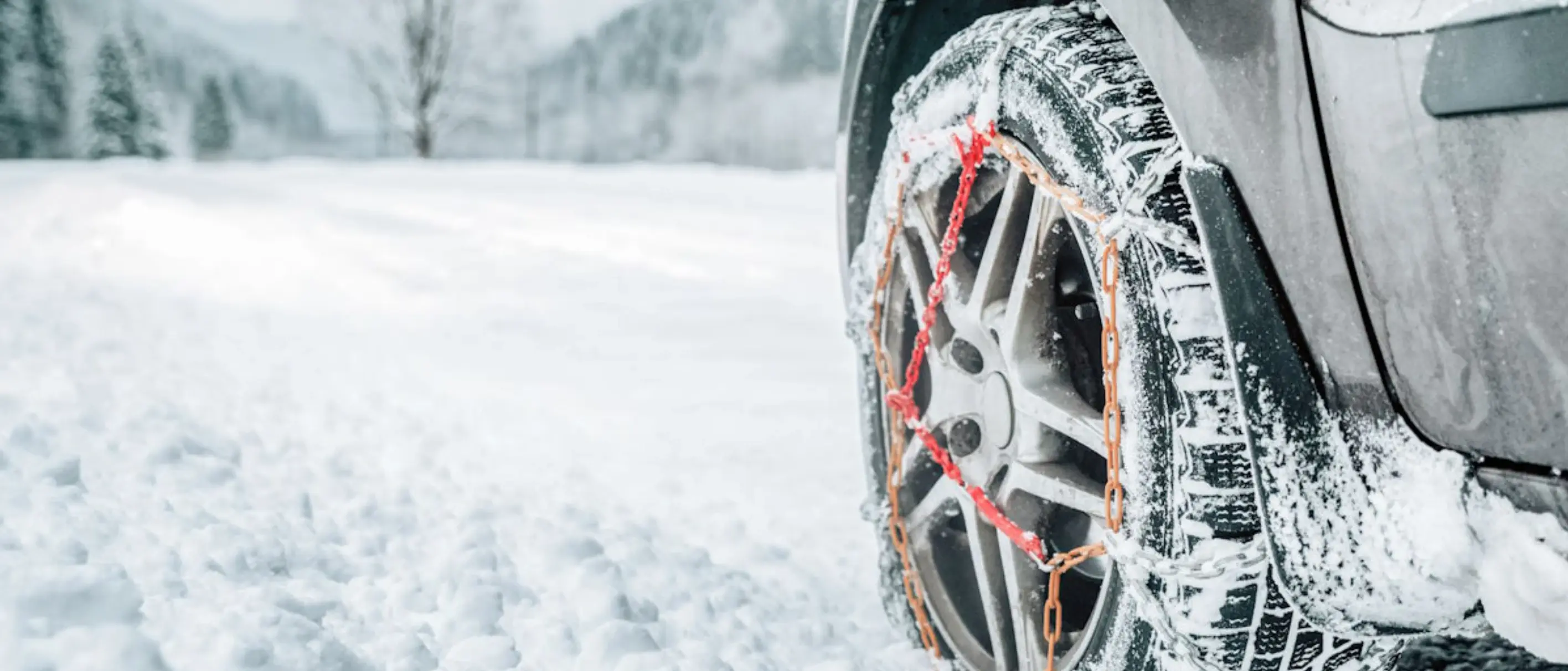 Hinterreifen eines Autos im Winter mit Schneeketten