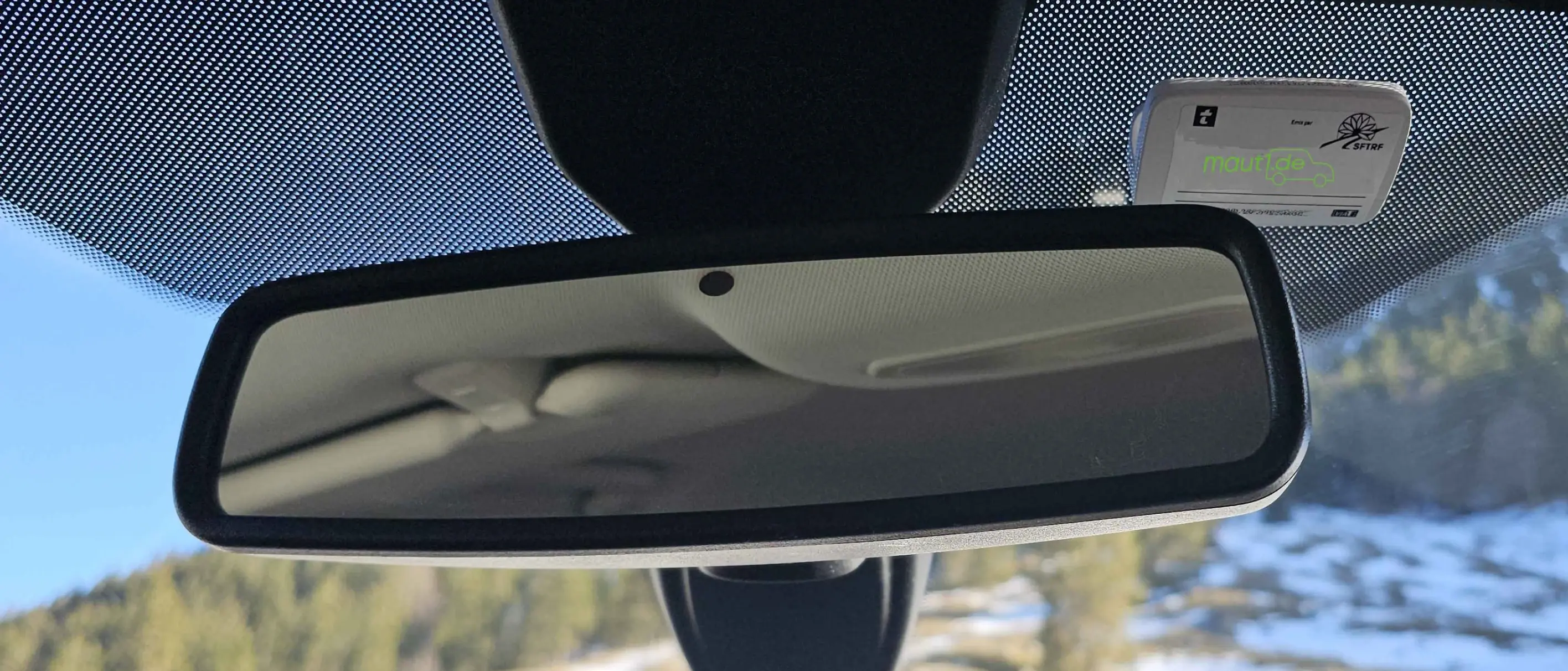 Bildausschnitt der Frontscheibe eines Fahrzeuges mit Rückspiegel und maut1 Mautbox