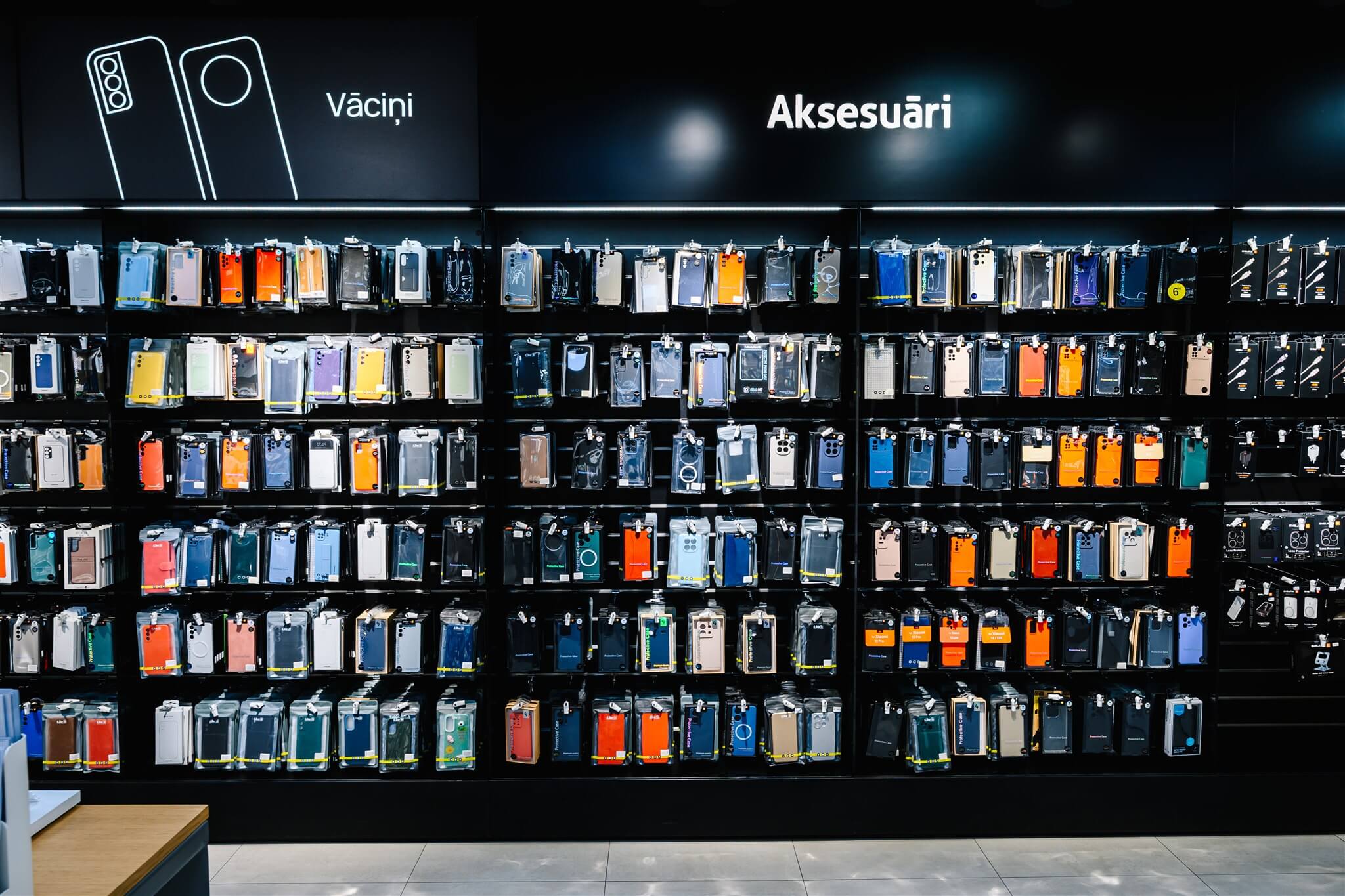 Display wall with various smartphone cases in colorful packaging, labeled "Aksesuarı," in a well-lit store.