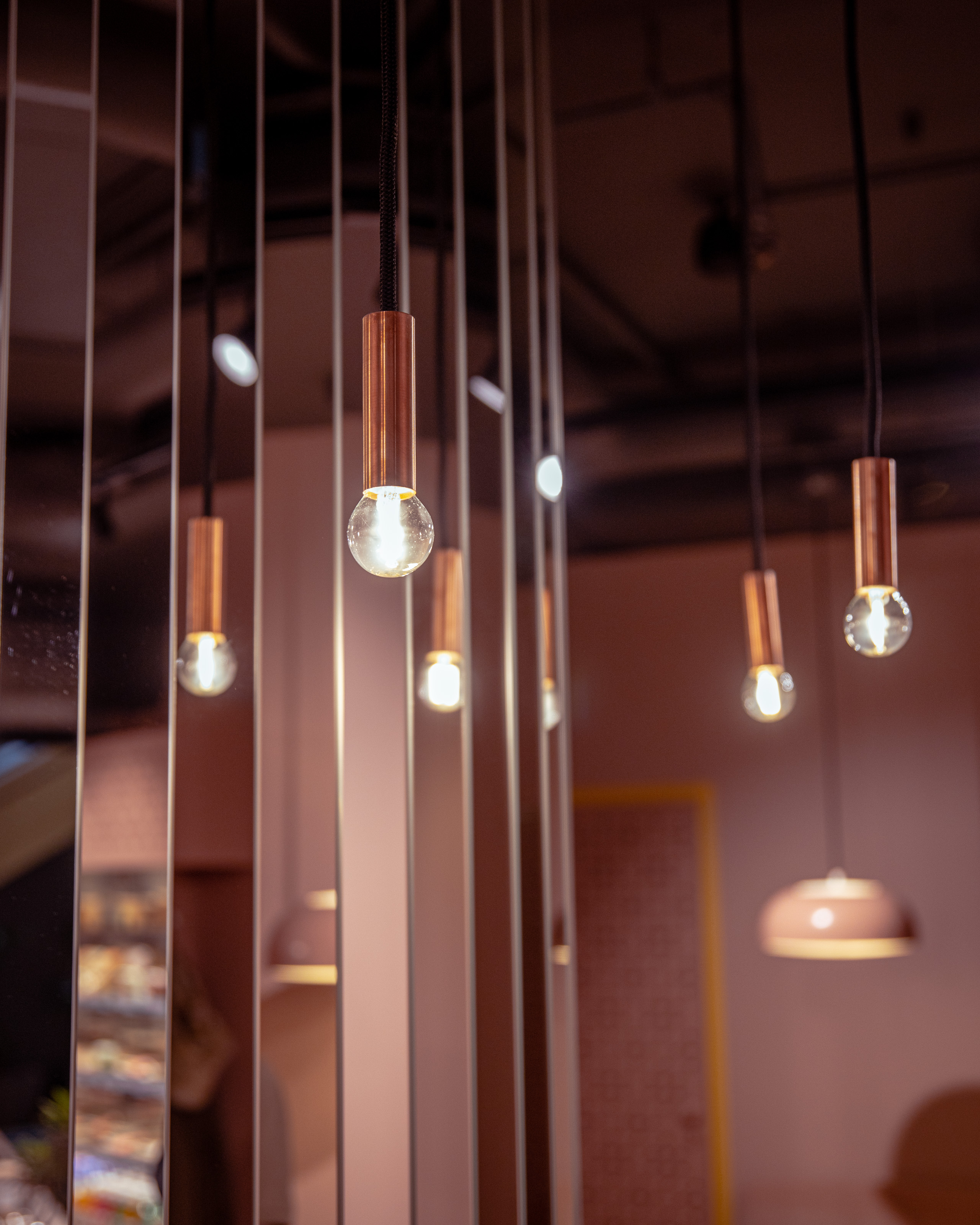Hanging pendant lights with exposed bulbs and copper fittings, creating a warm, ambient glow in a modern interior space.