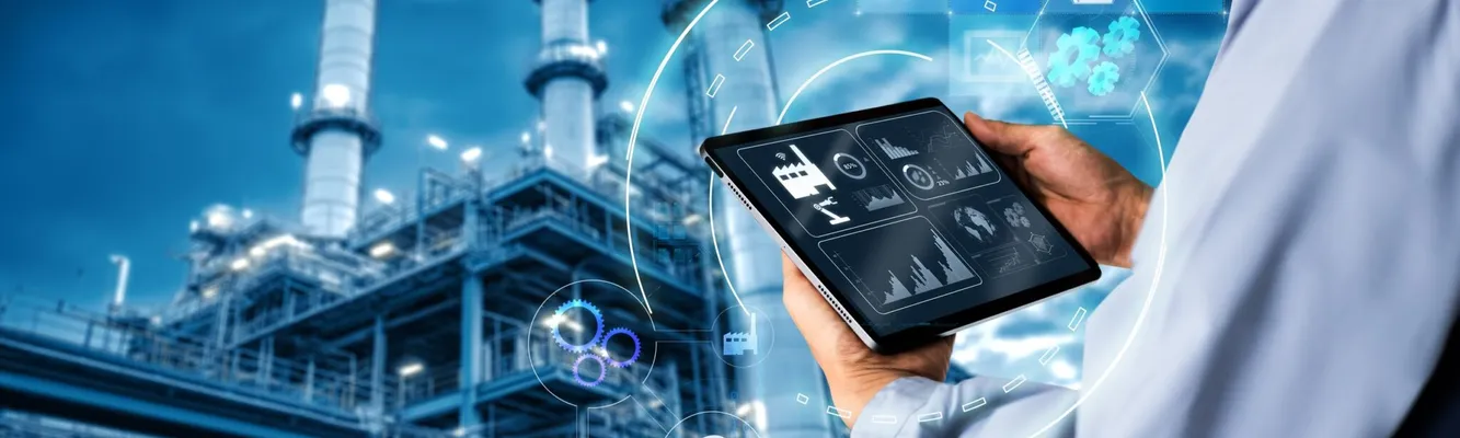 Person using a tablet with digital graphs in front of an industrial plant at night, symbolizing modern technology in industry.