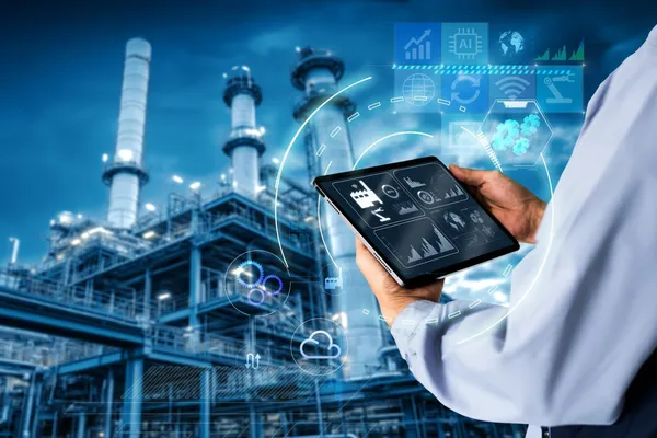 Person using a tablet with digital graphs in front of an industrial plant at night, symbolizing modern technology in industry.