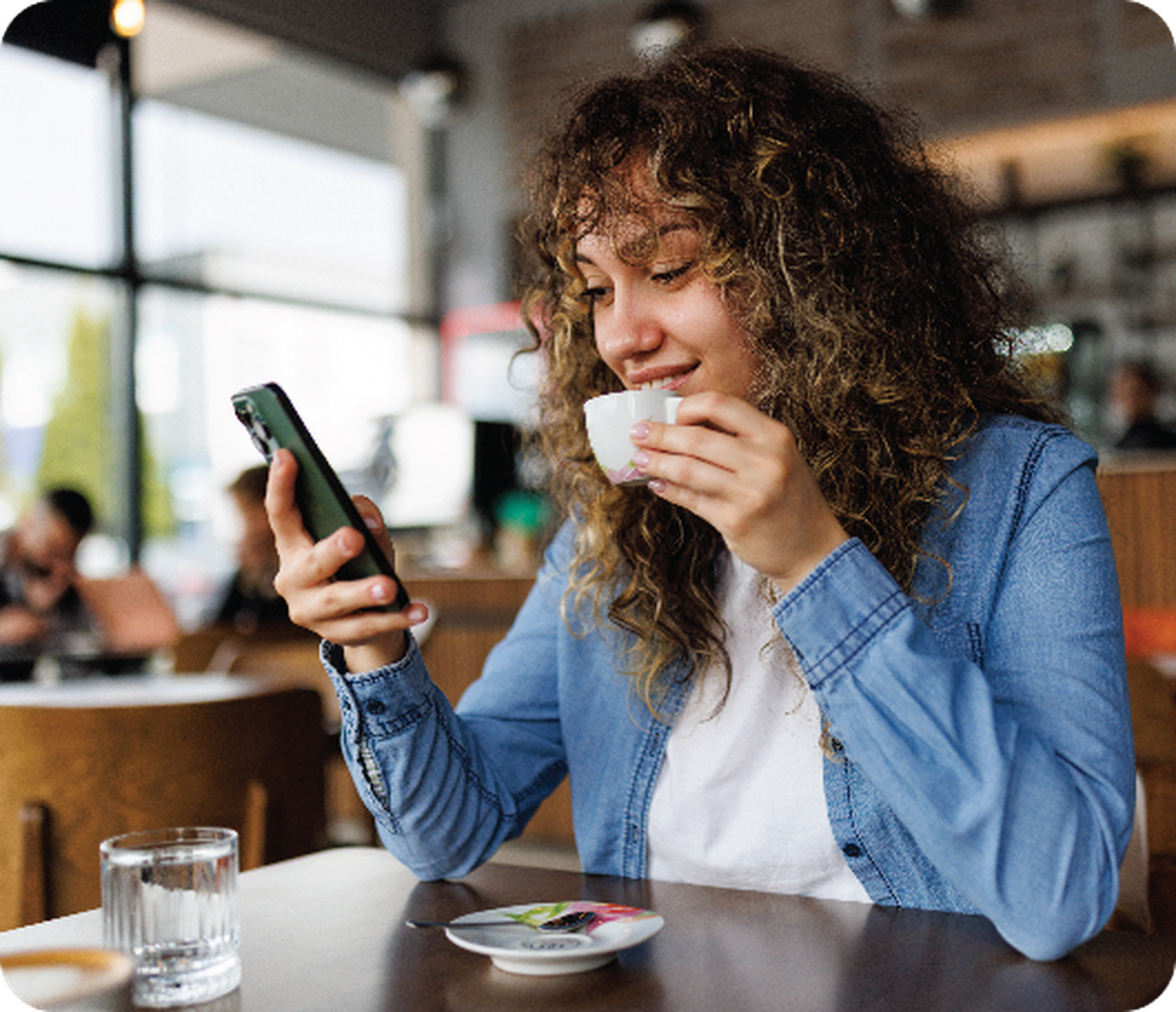 woman holding a coffee cup and smiling at her phone