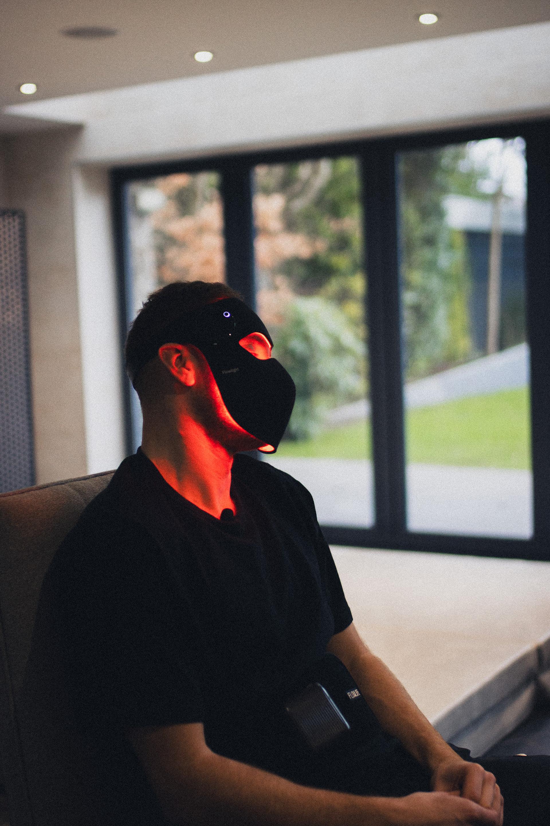 Footballer seated wearing a Flowlight LED face mask glowing red