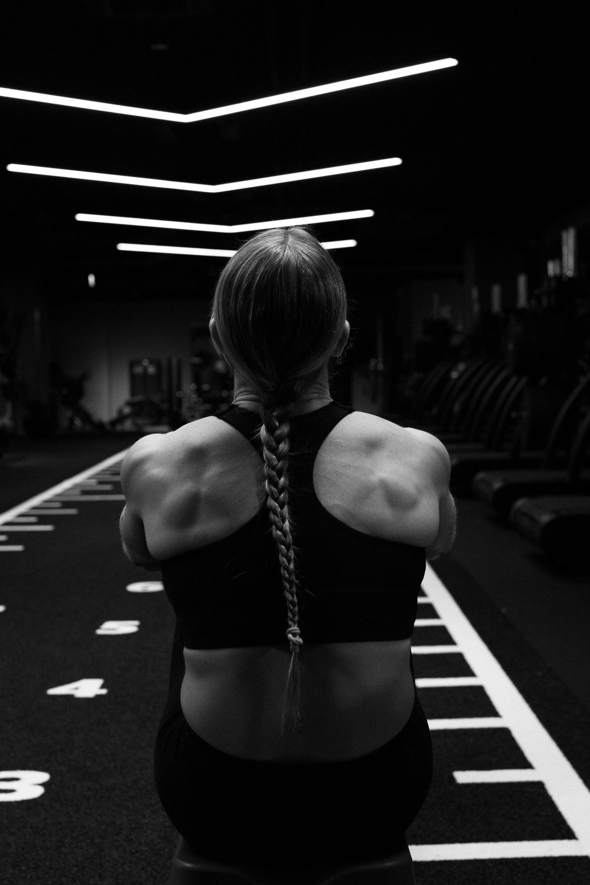 Athlete with a braid seen from behind on a gym turf track