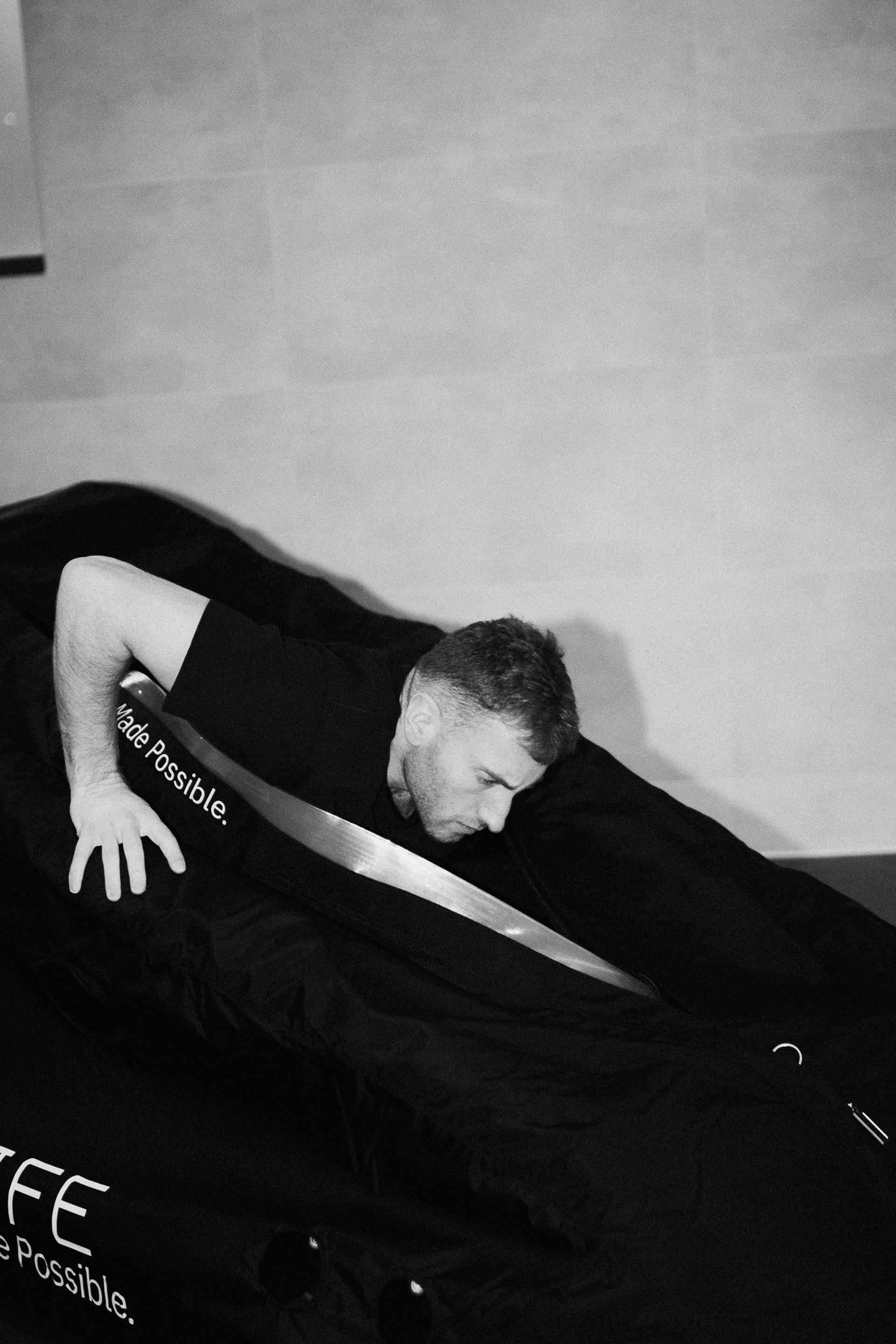 Footballer climbing into a black Flowchamber oxygen chamber